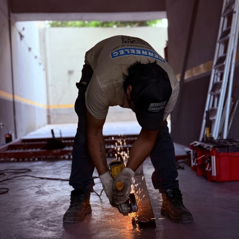 Se cortó una linga y el portón se vino abajo — Reemplazo del marco contenedor en portón levadizo. Reparación de un portón levadizo cuyo panel se dobló tras la rotura de una linga. Se realizó el reemplazo total del marco contenedor, asegurando su resistencia y funcionalidad. En la imagen, se observa el proceso de corte de perfiles para la soldadura del nuevo marco. Trabajo realizado por HERREELEC.